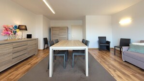 A modern living room with a dining table, sofas, and a cabinet. - Apartment on the coast for 6 people (MIDDELKERKE)