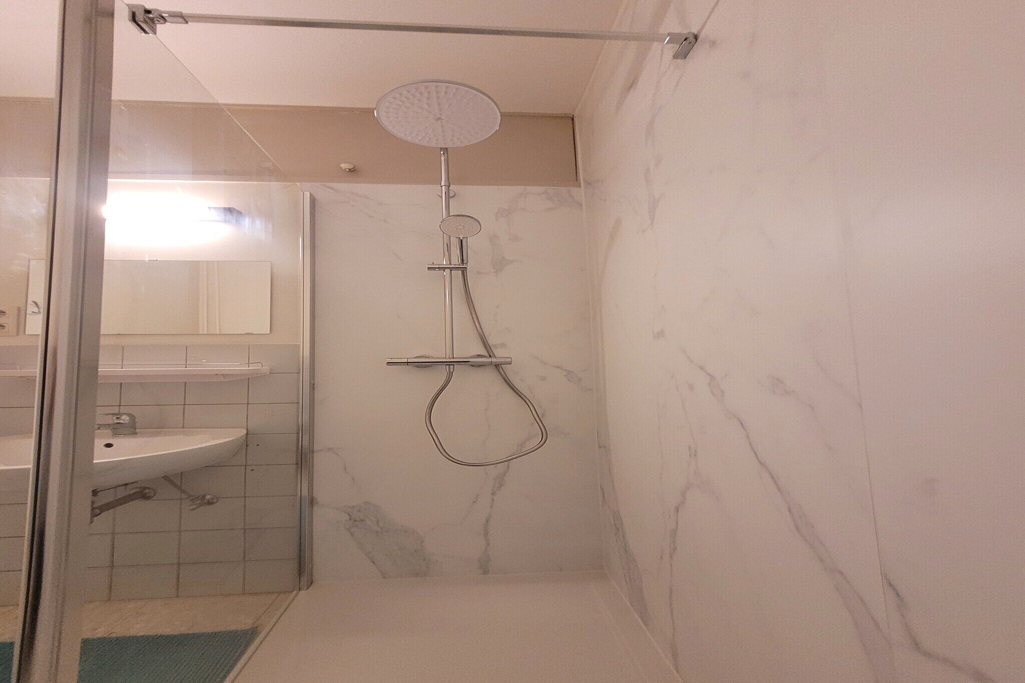 A bathroom with a shower, a sink, and a mirror.