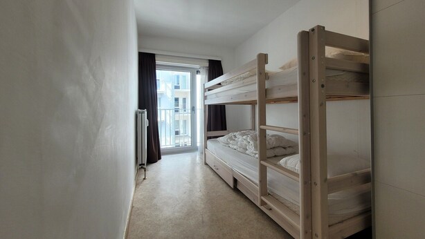 A narrow room with a bunk bed, a radiator, and a window with curtains. - Apartment on the coast for 6 people (MIDDELKERKE)