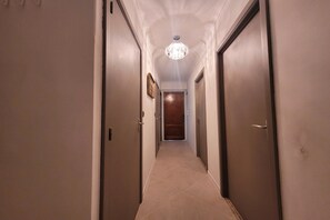 A hallway with doors on both sides, a chandelier, and a door at the end. - Apartment with Panoramic Sea Views (MIDDELKERKE)