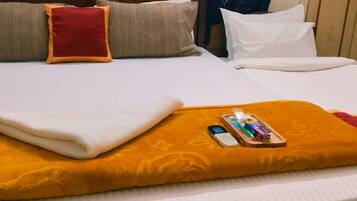 A neatly made bed with a folded white blanket, a red pillow, and a tray with toiletries.