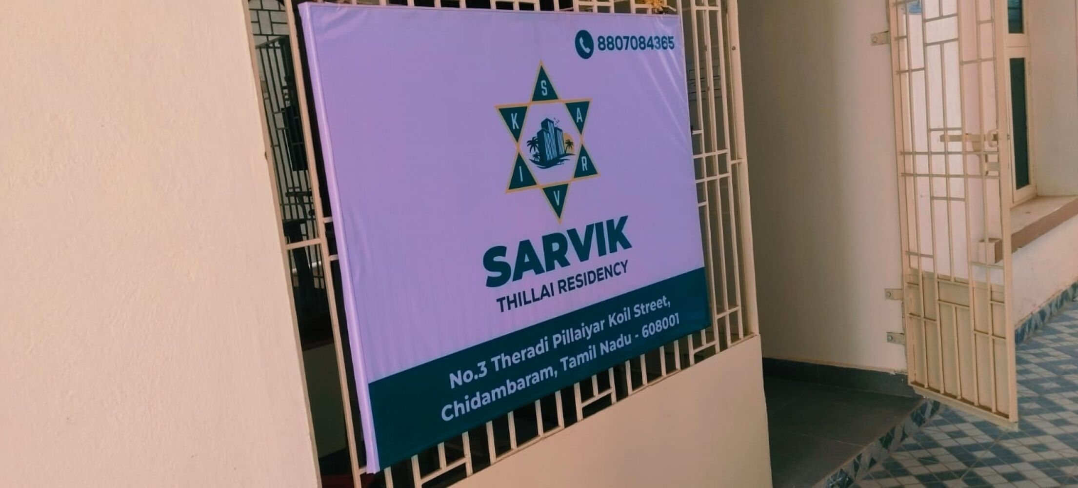 A sign for Sarvik Thilla Residency with contact information and address.