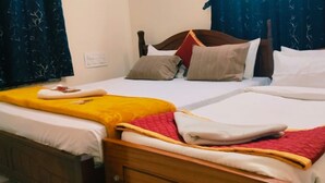 A hotel room with two beds, each with a different colored bedspread. There are pillows and a blanket on the beds. - Sarvik Thillai Residency  (Chidambaram)