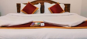 A neatly made bed with a wooden headboard, white bedding, and two red pillows. - Sarvik Thillai Residency  (Chidambaram)