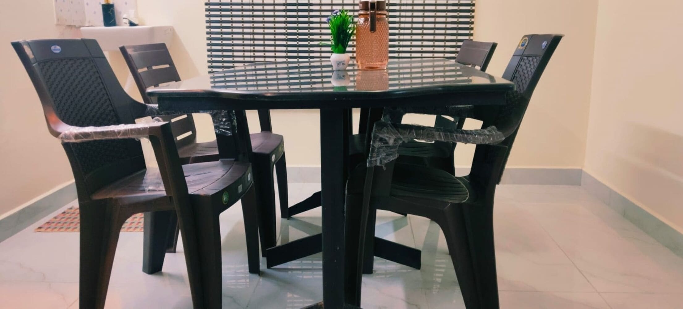 Une table à manger avec quatre chaises, un plateau en verre et une petite plante en pot posée sur la table.