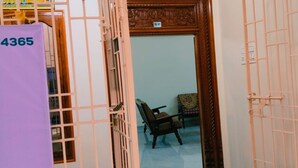 A room with a wooden door, a chair, and a purple object with the number 4365. - Sarvik Thillai Residency  (Chidambaram)