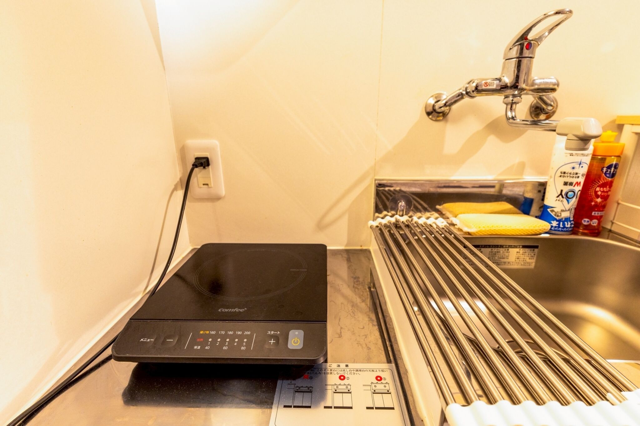 A compact kitchen with a coffee machine, a sink, and a faucet.