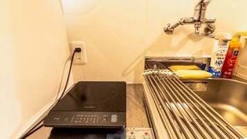 A compact kitchen with a coffee machine, a sink, and a faucet.