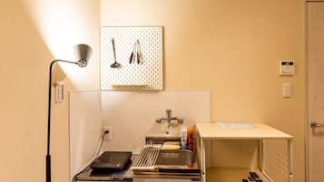 A compact kitchenette with a sink, a small countertop, and a wall-mounted pegboard with kitchen utensils.