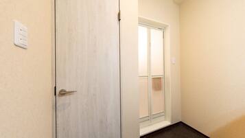 A hallway with a wooden door and a window with a view.