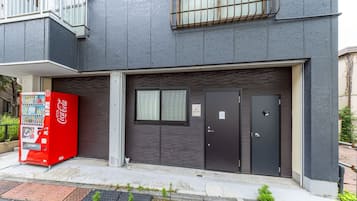 A building with a dark facade, a Coca-Cola vending machine, and a closed garage door.