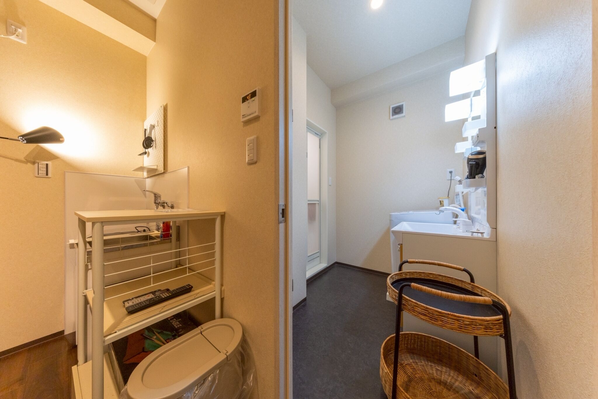 A hallway with a bathroom featuring a sink, mirror, and a wicker chair.