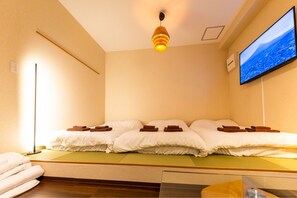 A room with a bed, a flat-screen TV on the wall, and a floor lamp. - Fukurouan (Toshimaku Kamiikebukuro)