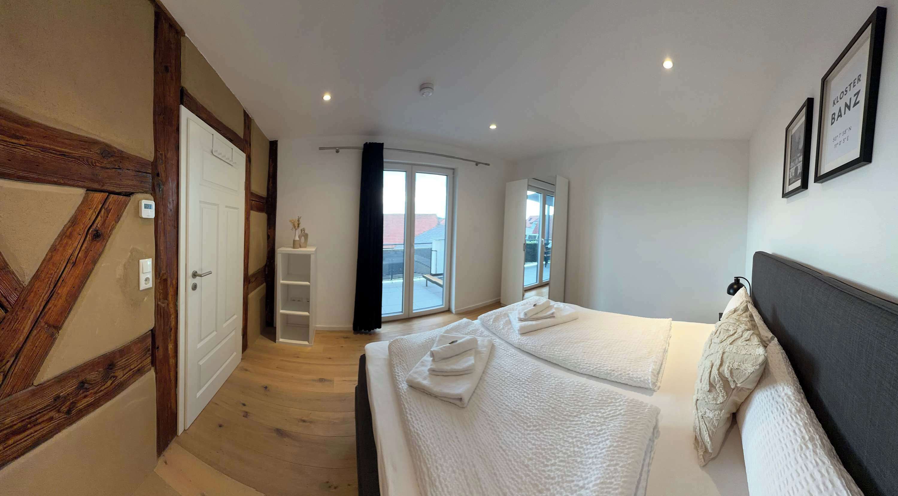 Ein Hotelzimmer mit zwei Betten, Holzboden, einem Balkon und Blick ins Freie.