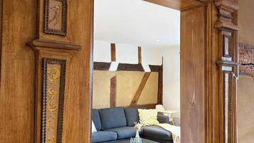 A wooden doorway leading to a living room with a sofa, a coffee table, and a fireplace.