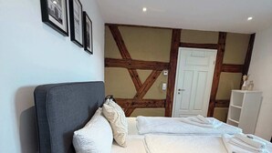 A bedroom with a bed, pillows, a bedside lamp, a wooden ceiling, and a white door. - Juraperle - Historisch und modern - Wohnung 5 (Bad Staffelstein)
