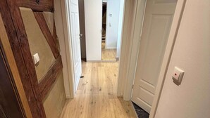 A hallway with wooden flooring, white walls, and open doors leading to other rooms. - Juraperle - Historisch und modern - Wohnung 5 (Bad Staffelstein)