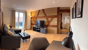 A modern living room with a sofa, a coffee table, and a TV stand. - Juraperle - Historisch und modern - Wohnung 5 (Bad Staffelstein)