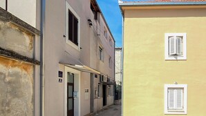 Eine enge Straße, gesäumt von Gebäuden mit Fenstern und Türen, mit blauem Himmel darüber.