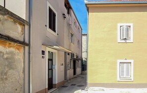 Eine enge Straße, gesäumt von Gebäuden mit Fenstern und Türen, mit blauem Himmel darüber.