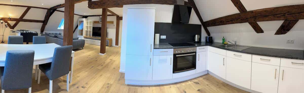 A modern kitchen with white cabinets, a black stove, and a wooden ceiling.