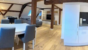 Une cuisine moderne avec des armoires blanches, une cuisinière noire et un plafond en bois.