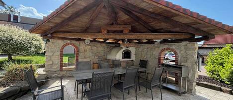 Un patio al aire libre con paredes de piedra, techo de madera y una estación de parrillada.