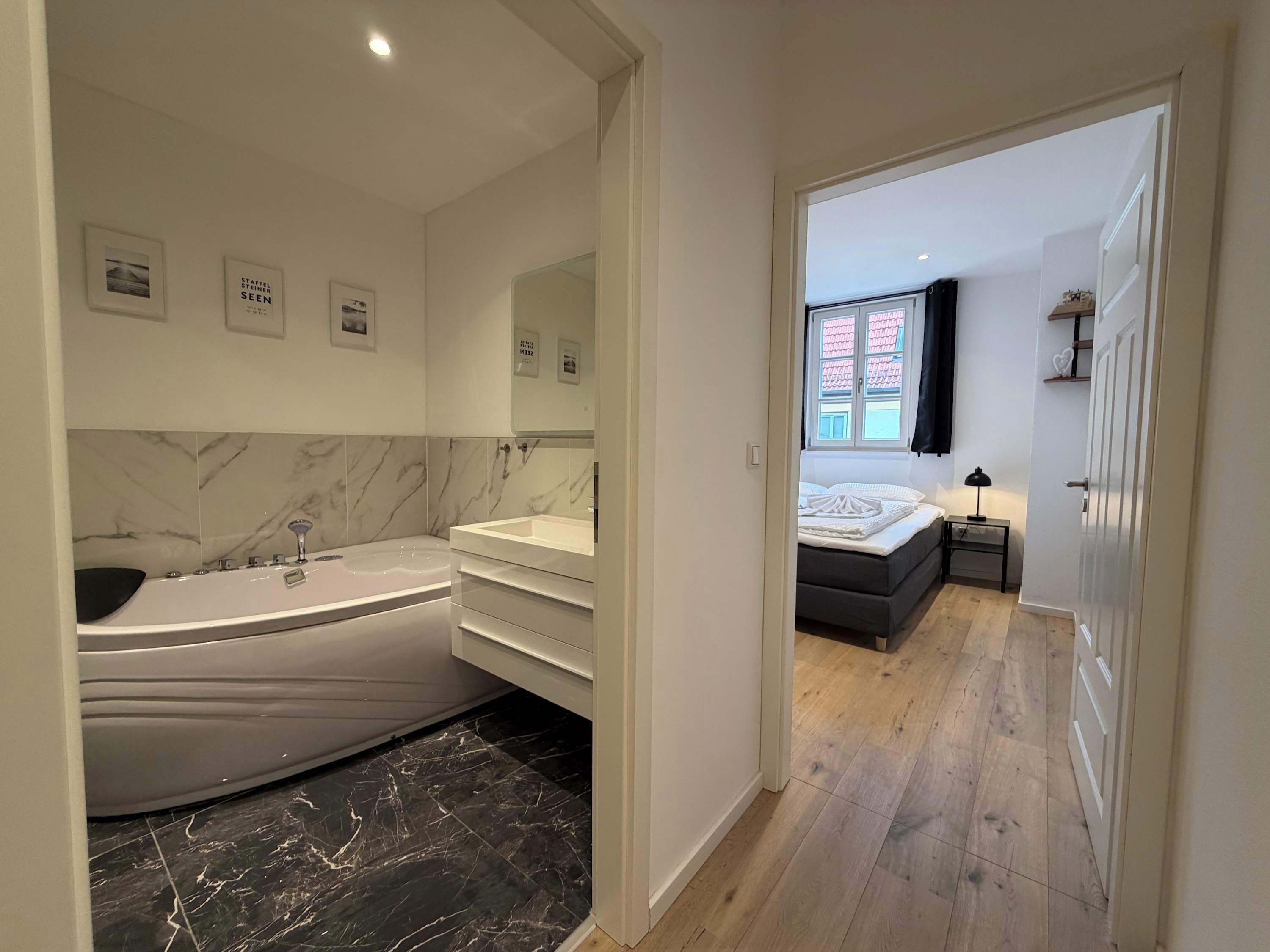 A modern bathroom with a marble vanity, a freestanding bathtub, and a large mirror.