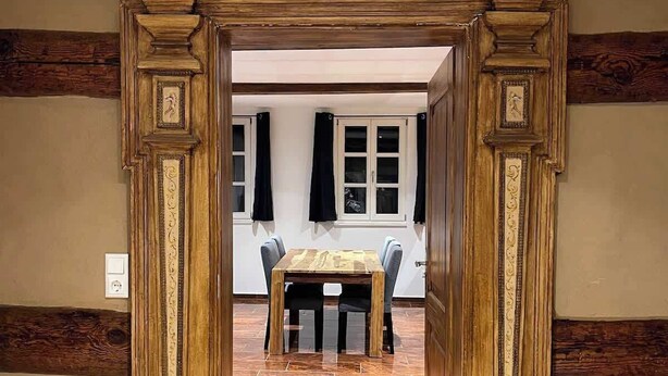 Una entrada con un arco de madera que conduce a un comedor con una mesa y sillas.