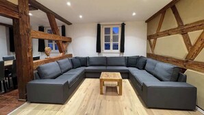 Una sala moderna con un sofá modular, una mesa de centro de madera y vigas de madera a la vista.
