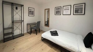 Un dormitorio con una cama, un escritorio y una silla. Hay cuadros en la pared.