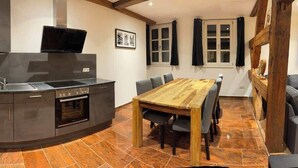 Una cocina moderna con microondas integrado, horno y televisor de pantalla plana. Hay una mesa de comedor de madera con sillas.