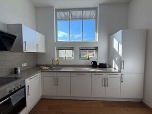 A modern kitchen with white cabinets, a stainless steel range, and a window with a view.