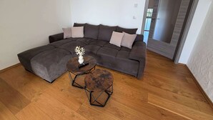 Ein modernes Wohnzimmer mit einer Eckcouch, zwei runden Couchtischen und Holzdielen.