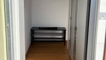 Un passadís amb una banca, una perxa amb diverses hamaques i una porta a la dreta.