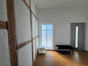 Une pièce dont la structure est constituée de poutres en bois, avec un banc, une porte et une fenêtre.