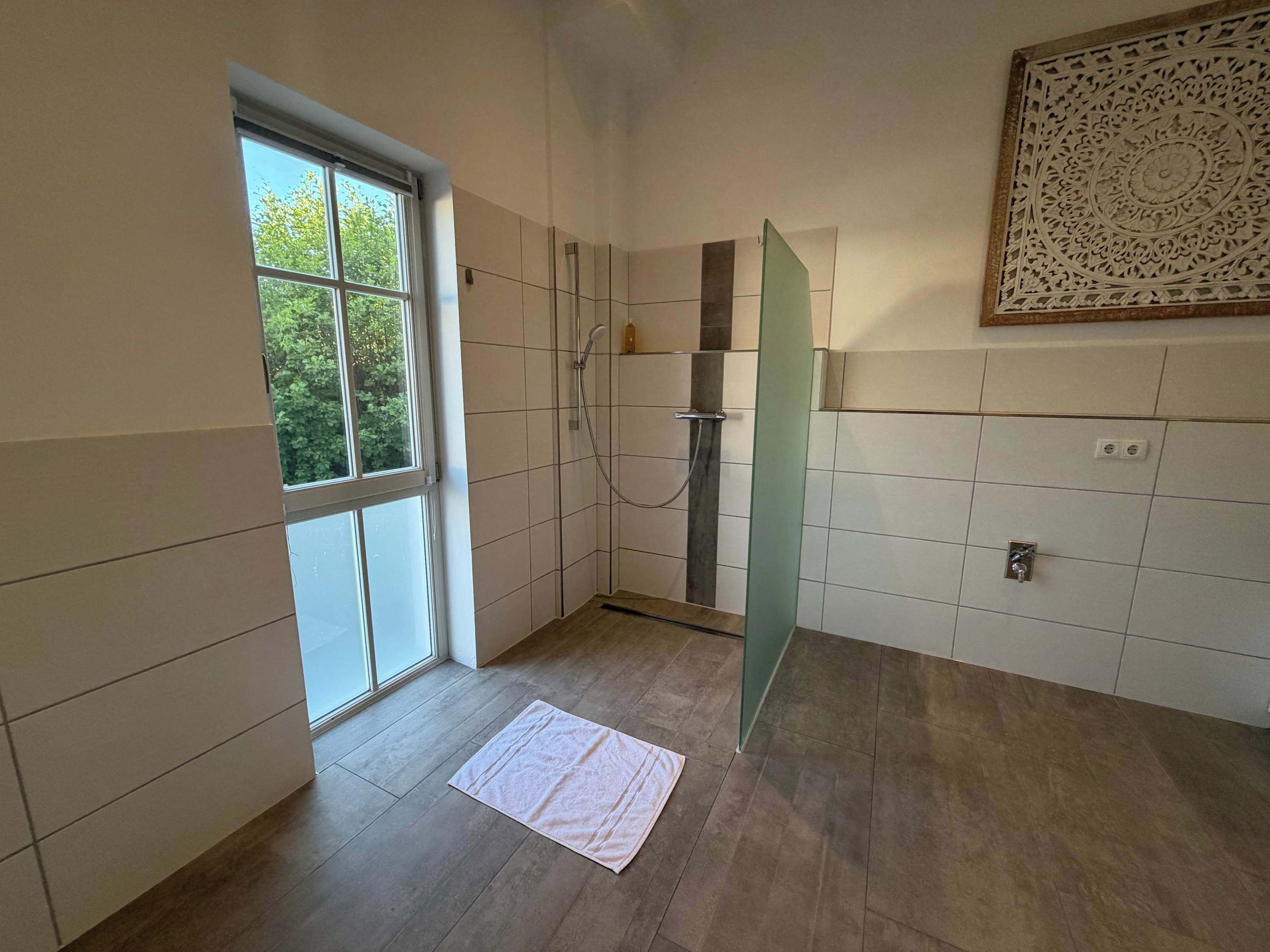 Une salle de bain avec une douche, une fenêtre et un élément décoratif mural.