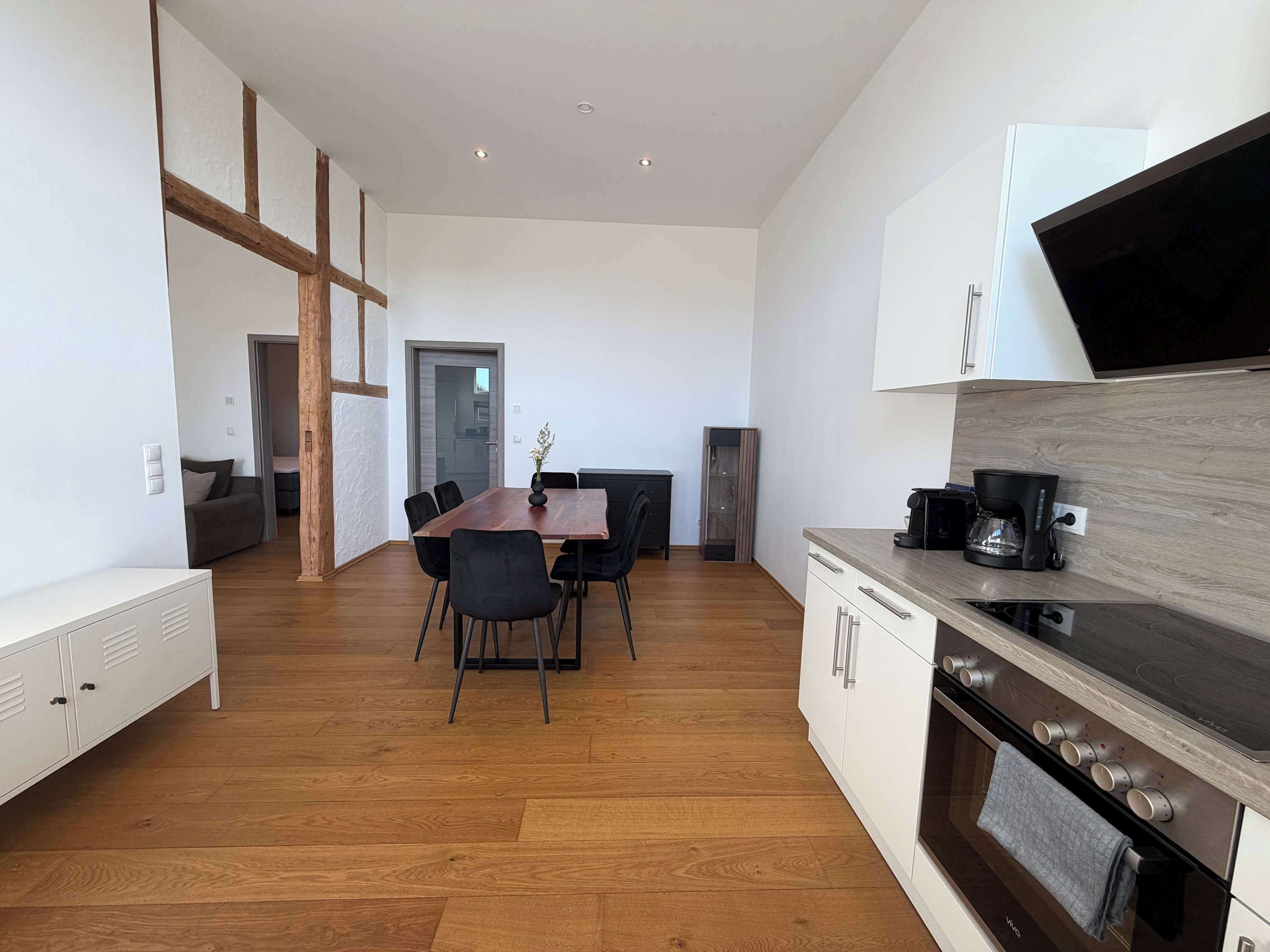 Een moderne keuken met een houten aanrecht, een ingebouwde oven, en een eetgedeelte met een houten tafel en stoelen.
