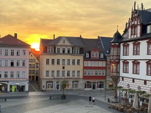 A European town square with historic buildings, a central open space, and a sunset in the background. - City Diamond - Coburg's most central apartments (Coburg)