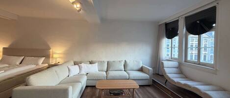 A modern living room with a sectional sofa, a small wooden coffee table, and a window with curtains.