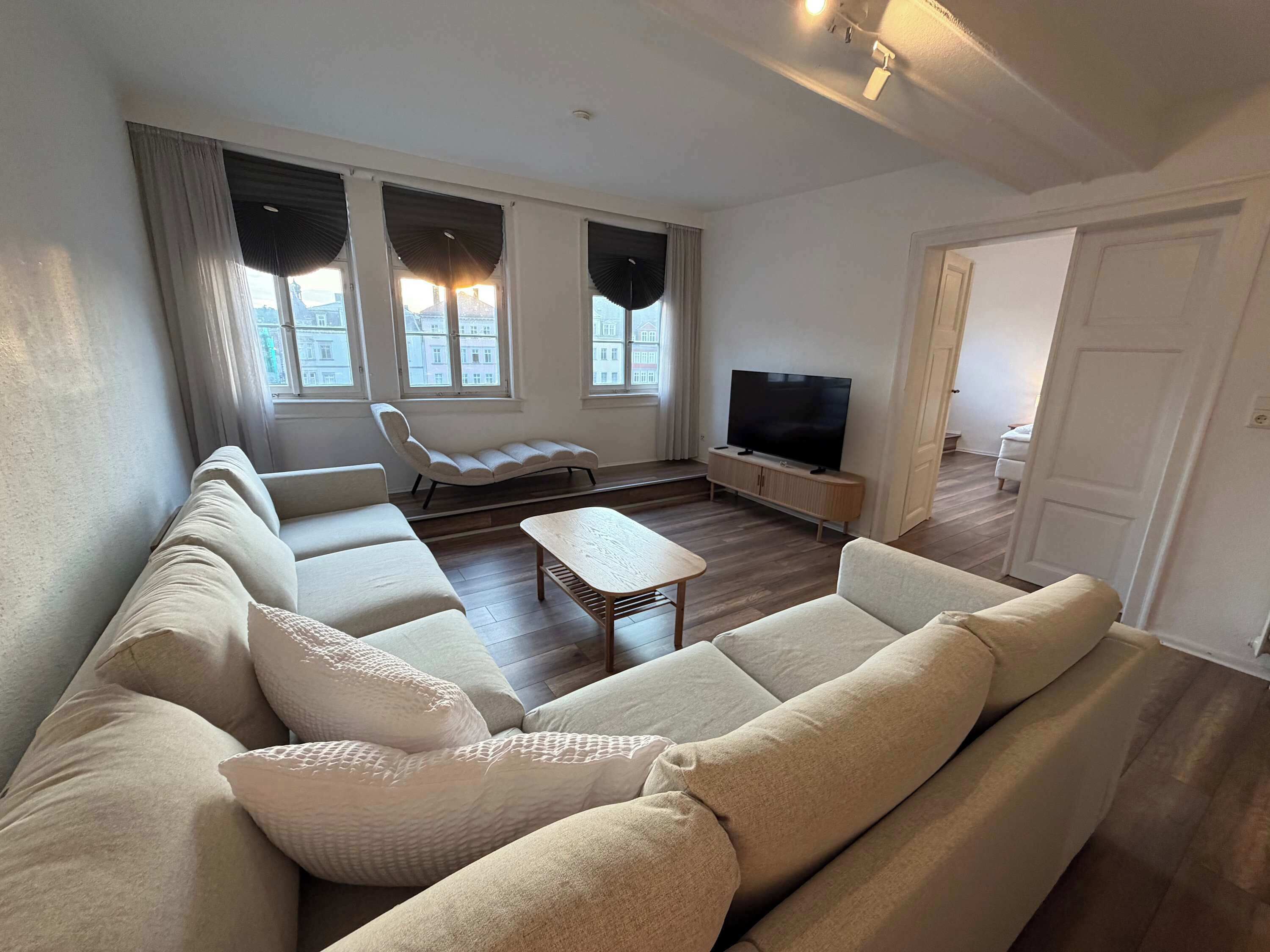 A living room with a sofa, a chair, a coffee table, and a TV.