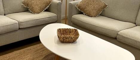 A living room with a sofa, two decorative pillows, a floor lamp, and a woven coffee table.