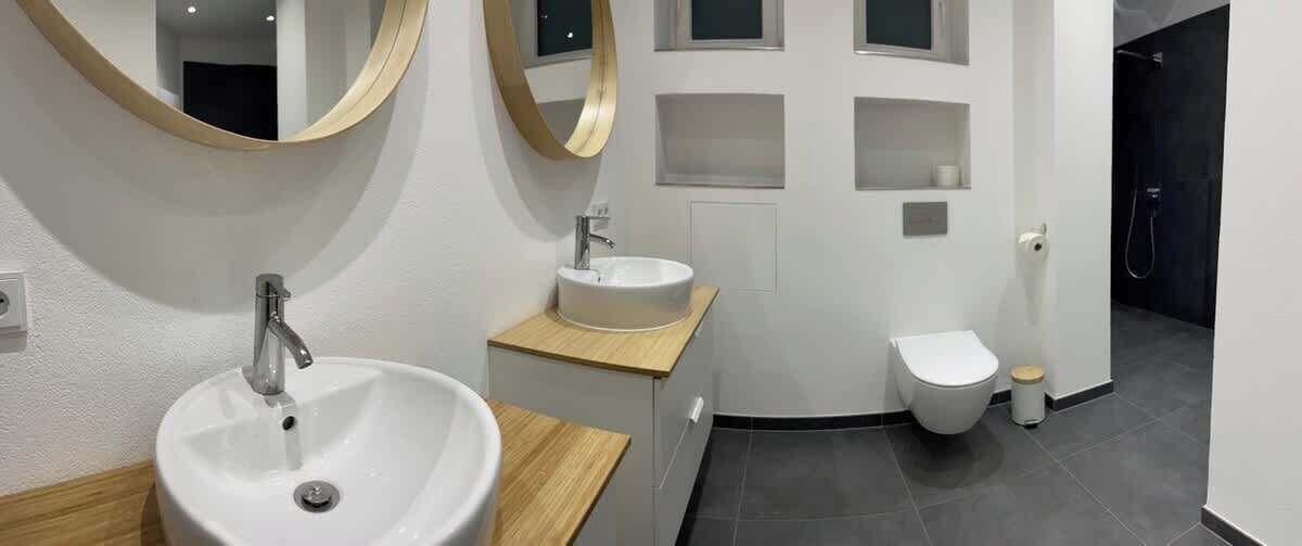 Ein modernes Badezimmer mit zwei Waschbecken, einer Toilette und einer Dusche.