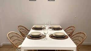 Un tavolo da pranzo apparecchiato con piatti, bicchieri e posate, circondato da sedie in vimini.