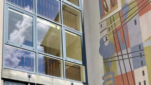 Un edificio con una facciata in vetro, una scala in metallo e un murale colorato sulla parete.