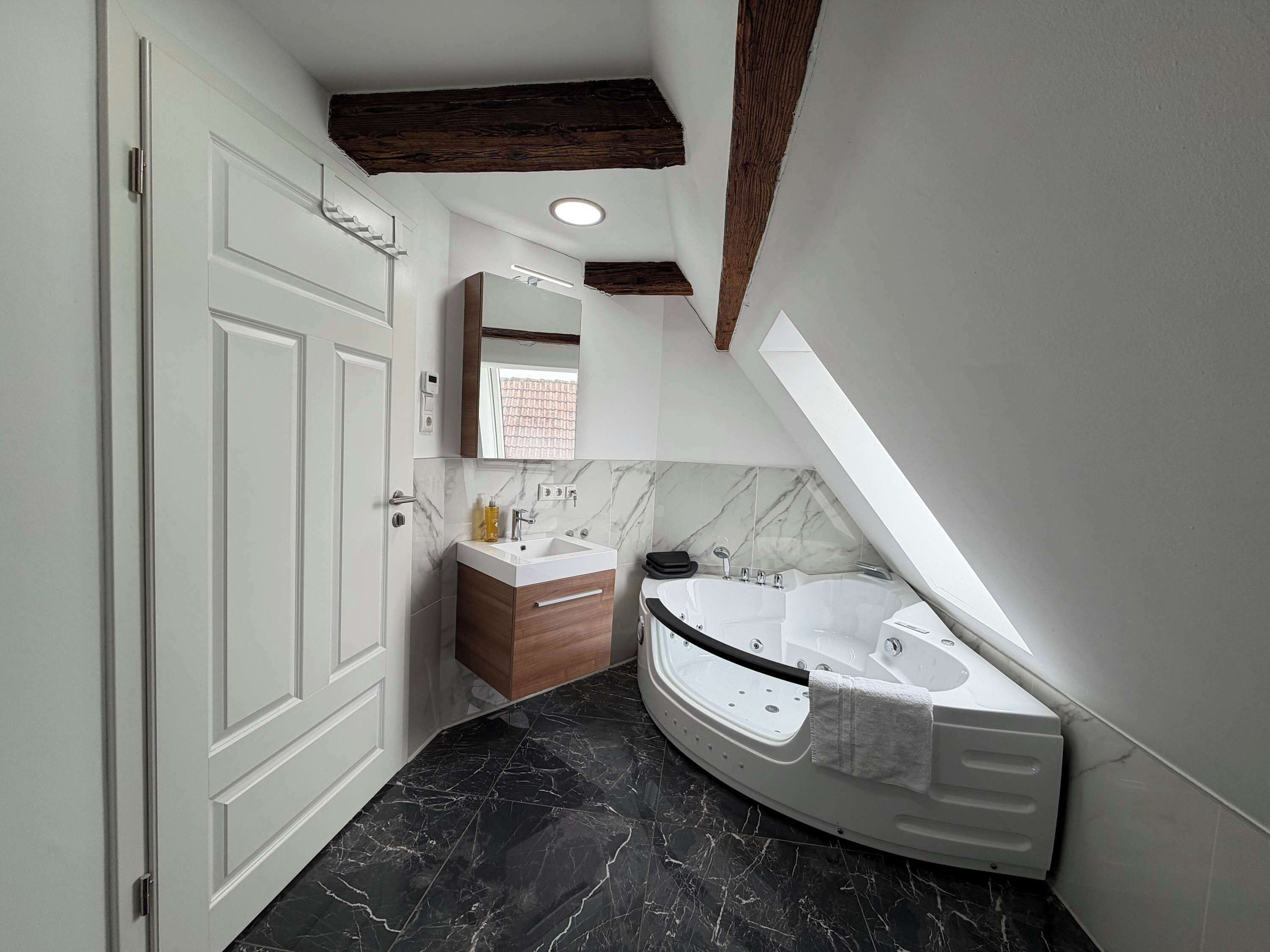 Une salle de bain moderne avec une baignoire sur pieds, un meuble-lavabo avec un miroir et une porte.