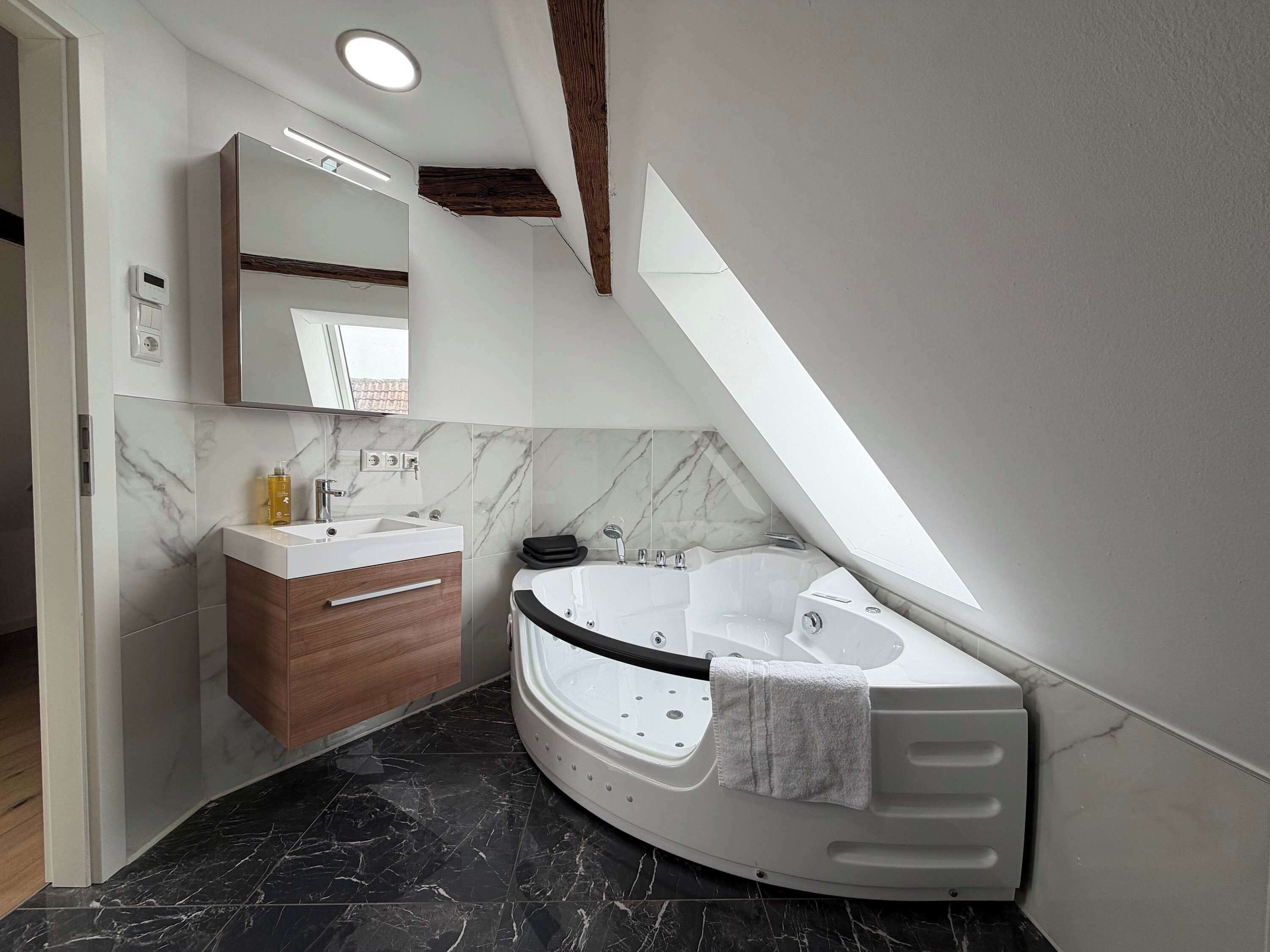 Un bagno moderno con una vasca da bagno dalla forma curva, un mobile toilette con specchio e pavimento in marmo.