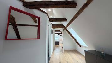 A hallway with wooden beams, a red-framed mirror, and a dark-toned cabinet.