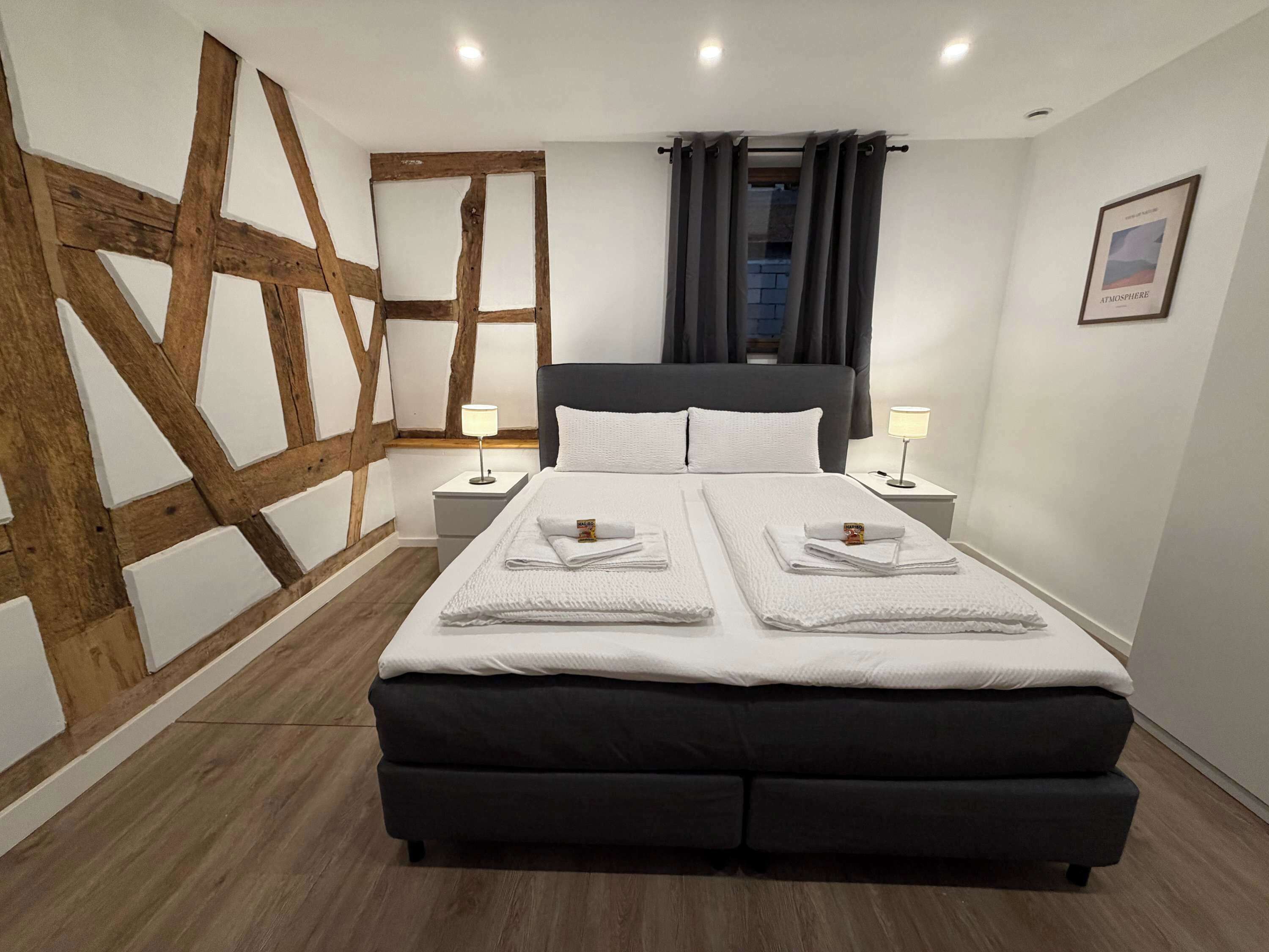 A modern bedroom with a large bed, two bedside tables, and a wooden accent wall.