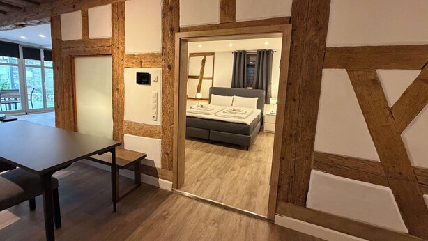 Quarto com teto de madeira, cama, mesa de cabeceira e janela.